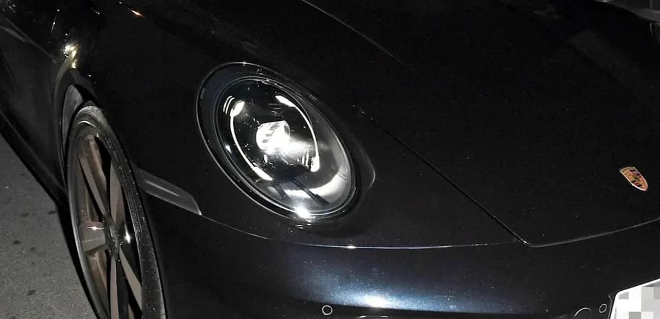Dos hombres en un Porsche negro estacionado