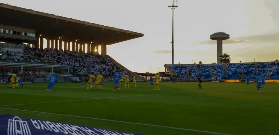 Jugadores compitiendo en partido de fútbol al atardecer