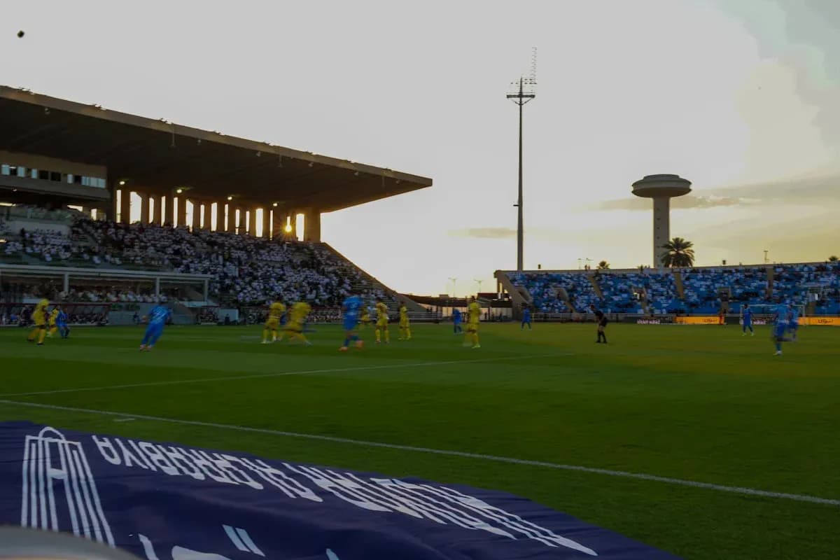 Jugadores compitiendo en partido de fútbol al atardecer