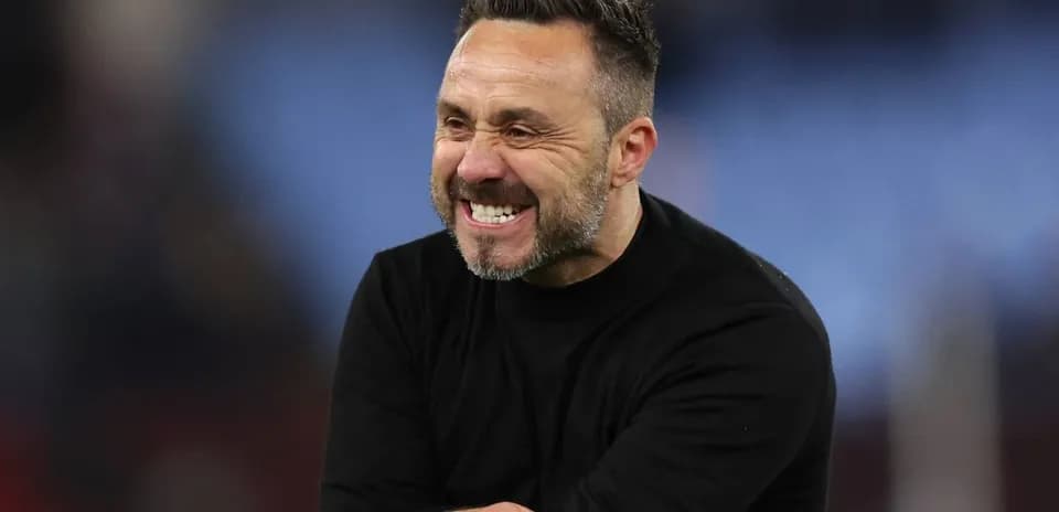 Entrenador sonriendo durante un partido en el campo