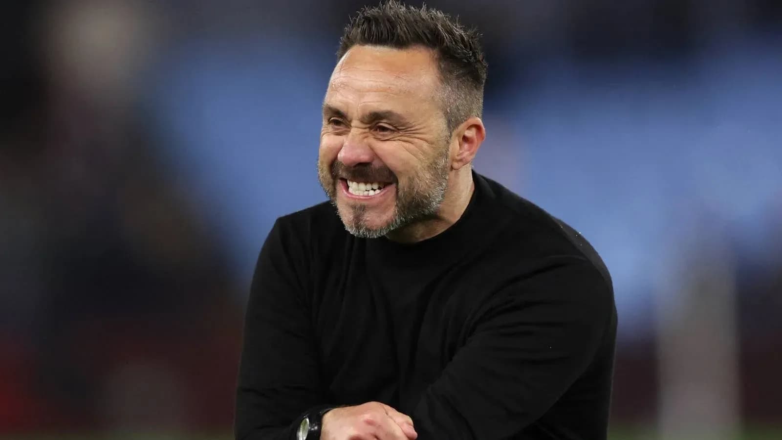 Entrenador sonriendo durante un partido en el campo