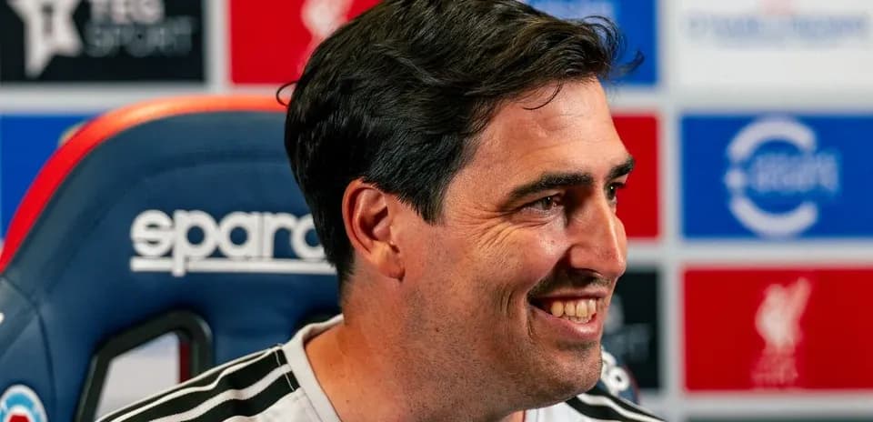 Entrenador sonriendo durante conferencia de prensa