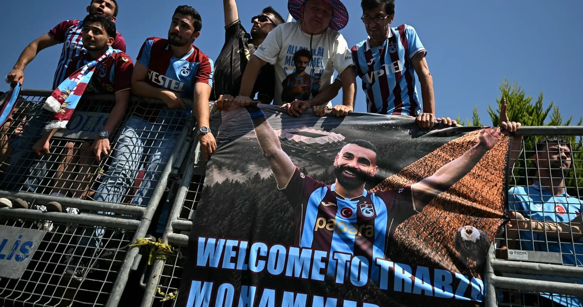 Aficionados sosteniendo un banner de bienvenida en estadio