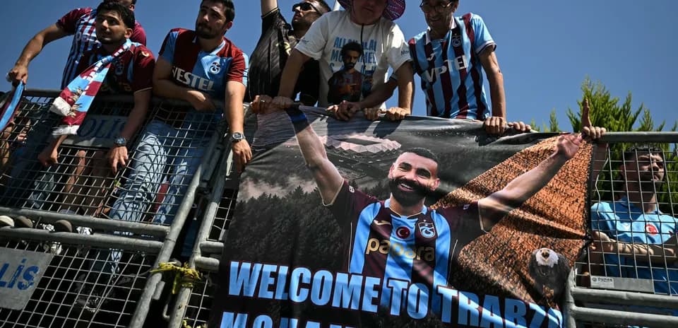 Aficionados sosteniendo un banner de bienvenida en estadio