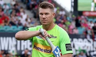 Jugador sosteniendo su bate en el campo de cricket