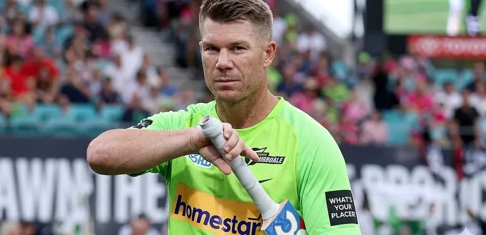 Jugador sosteniendo su bate en el campo de cricket