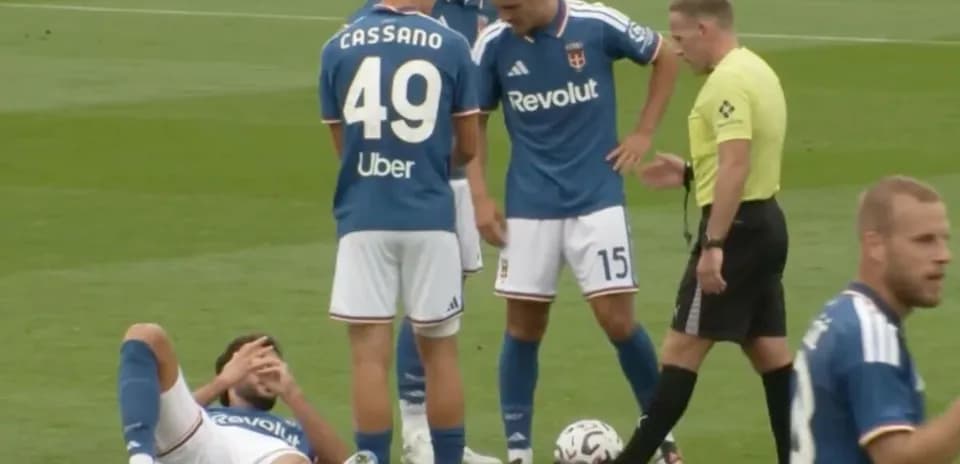 Jugador en el suelo con compañeros y árbitro cerca