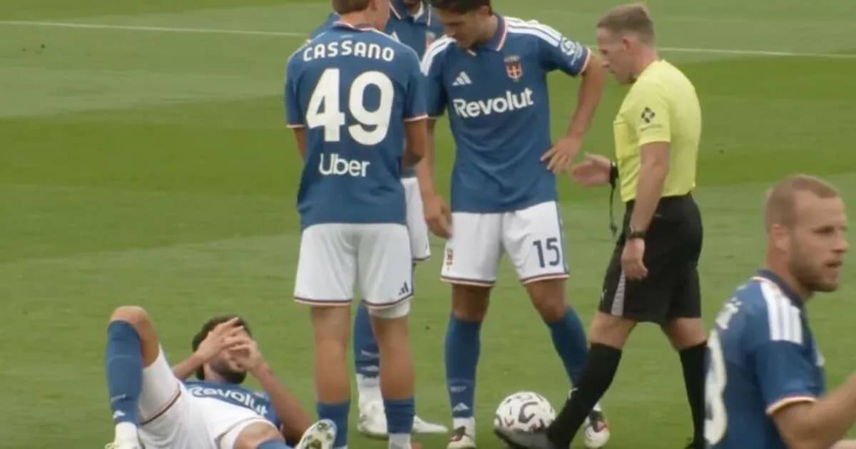 Jugador en el suelo con compañeros y árbitro cerca
