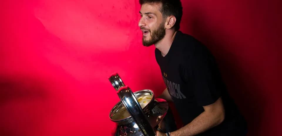 Jugador sosteniendo trofeo frente a fondo rojo