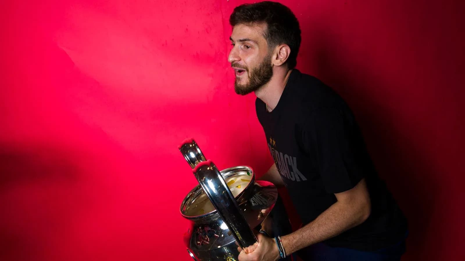 Jugador sosteniendo trofeo frente a fondo rojo