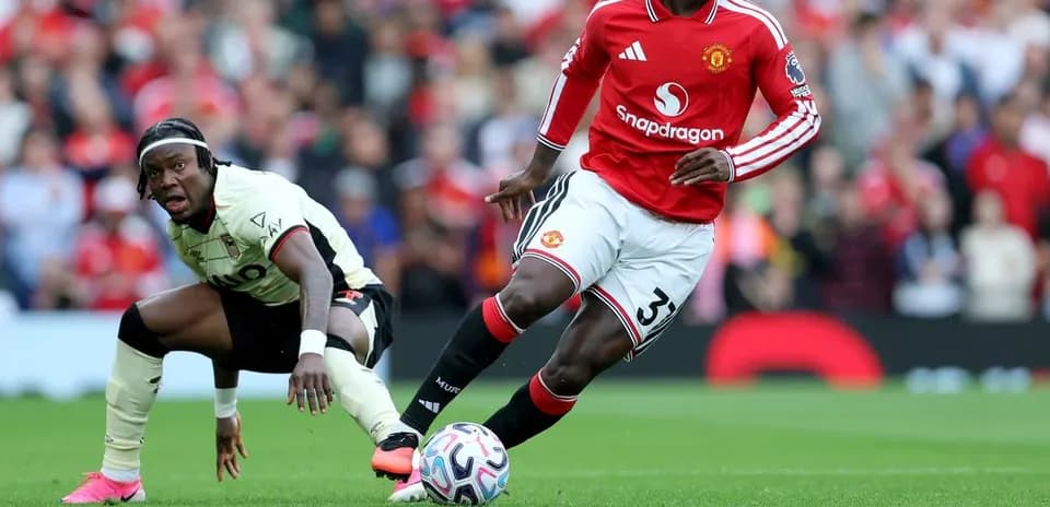Jugador de Manchester United driblando mientras rival cae