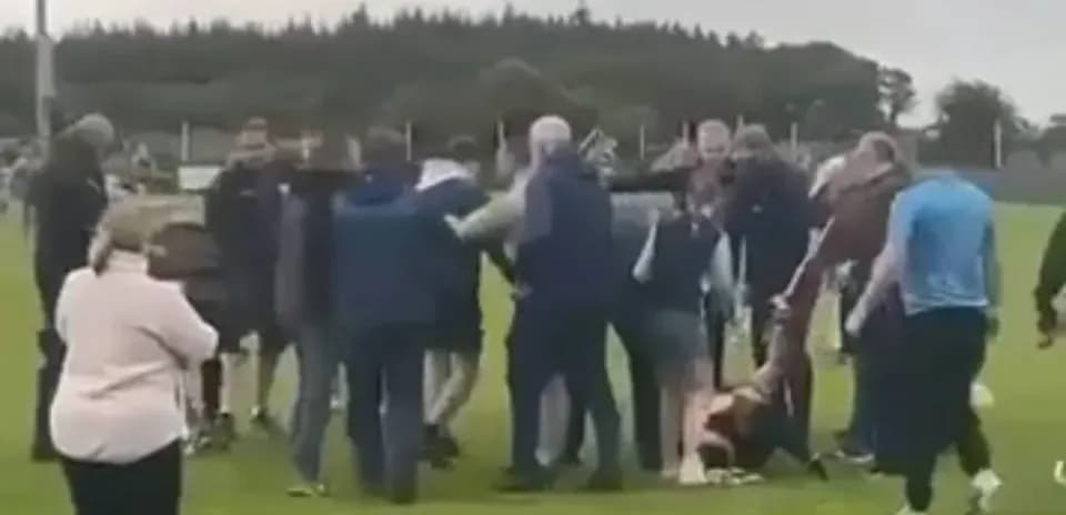 Multitud rodeando a jugadores en el campo de fútbol