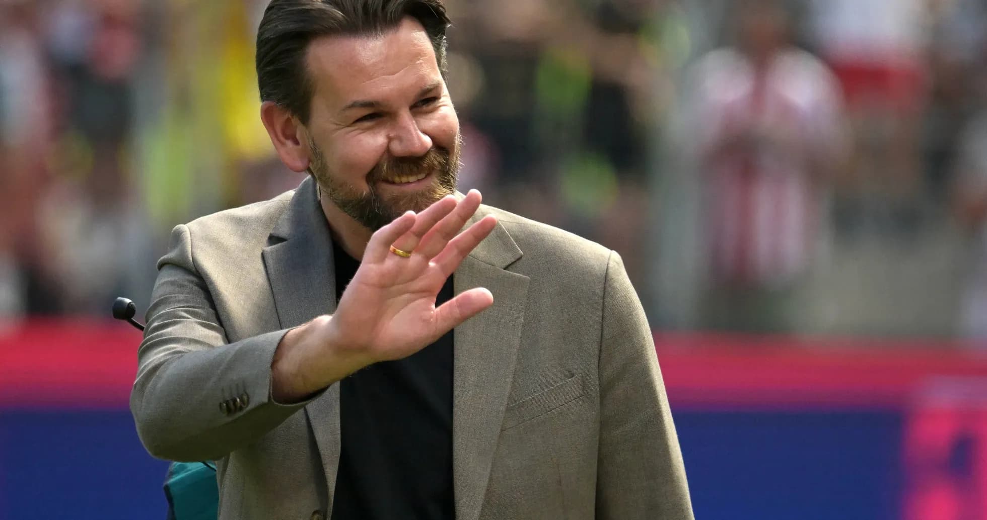 Hombre sonriendo y saludando en un evento deportivo