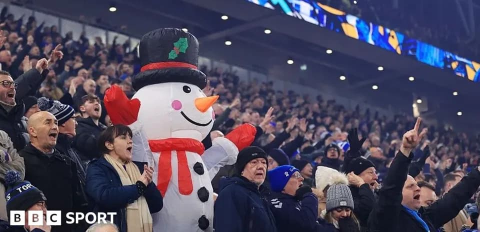 A crowd cheering with a large snowman mascot