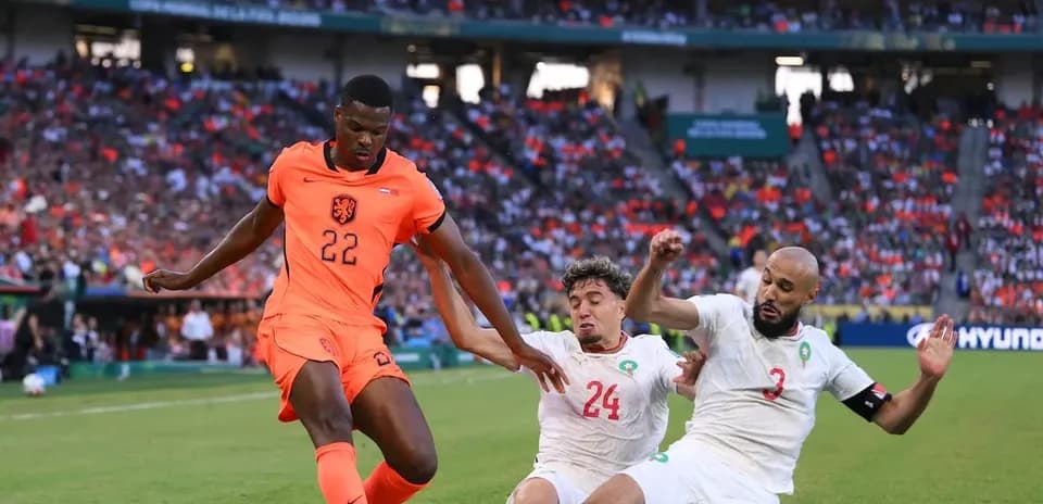 Jugador de Países Bajos driblando entre dos defensores