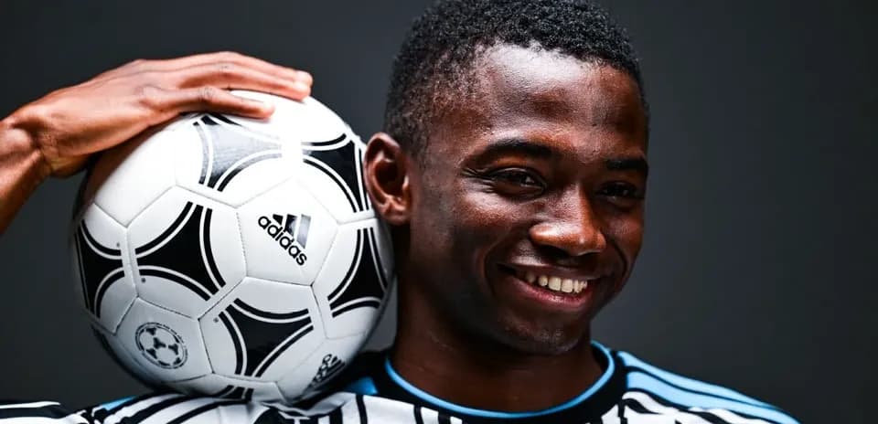 Jugador sosteniendo un balón de fútbol sonriendo