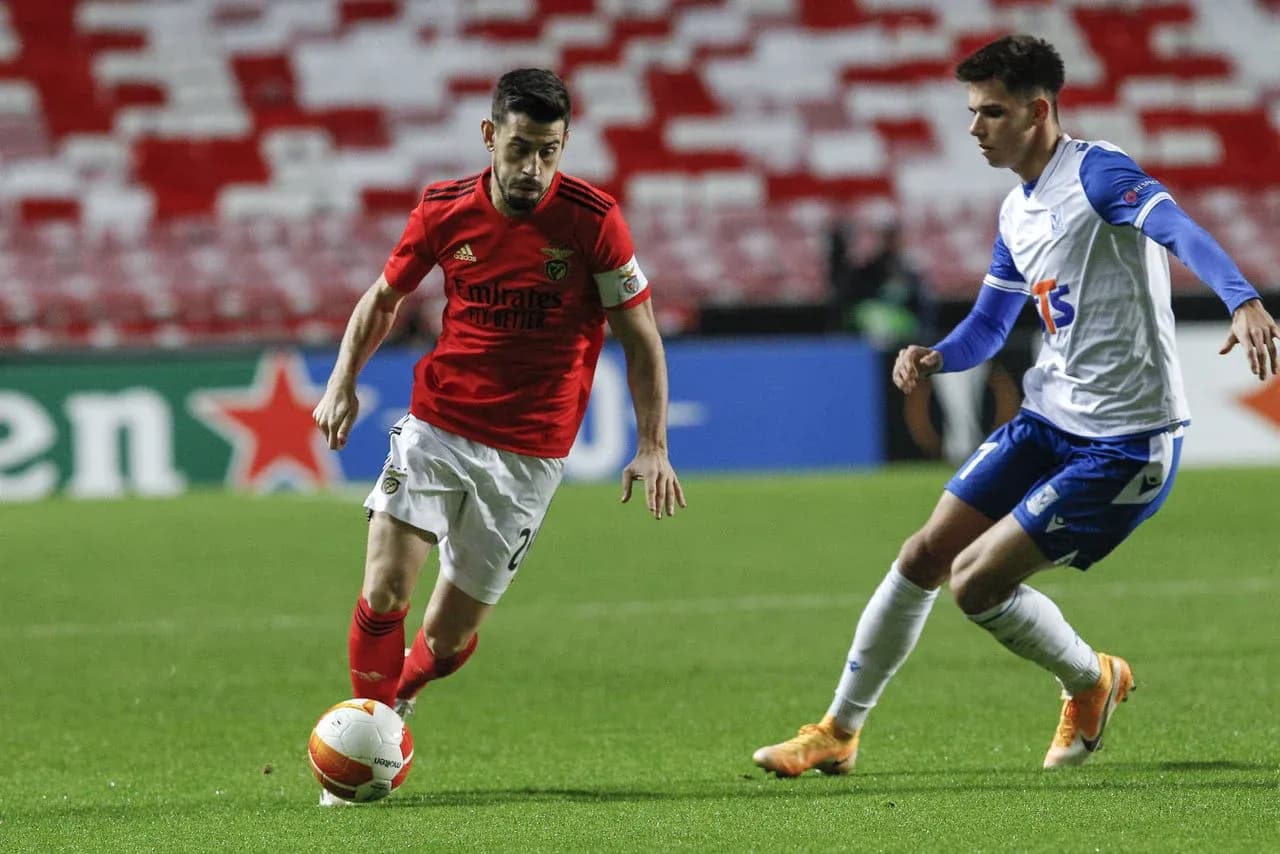 Jugador de Benfica driblando a rival de Lech Poznan