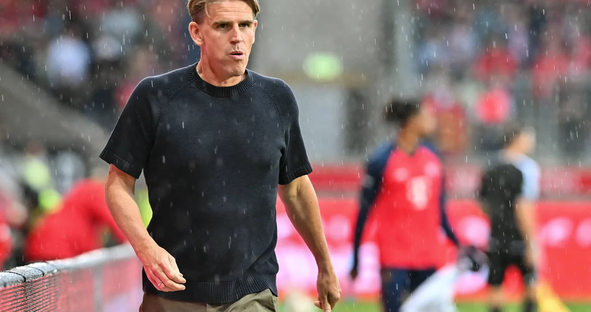 Entrenador caminando bajo la lluvia en el campo