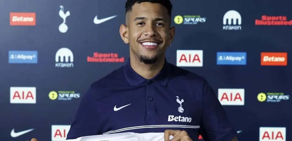 Jugador sonriente sosteniendo camiseta de Tottenham