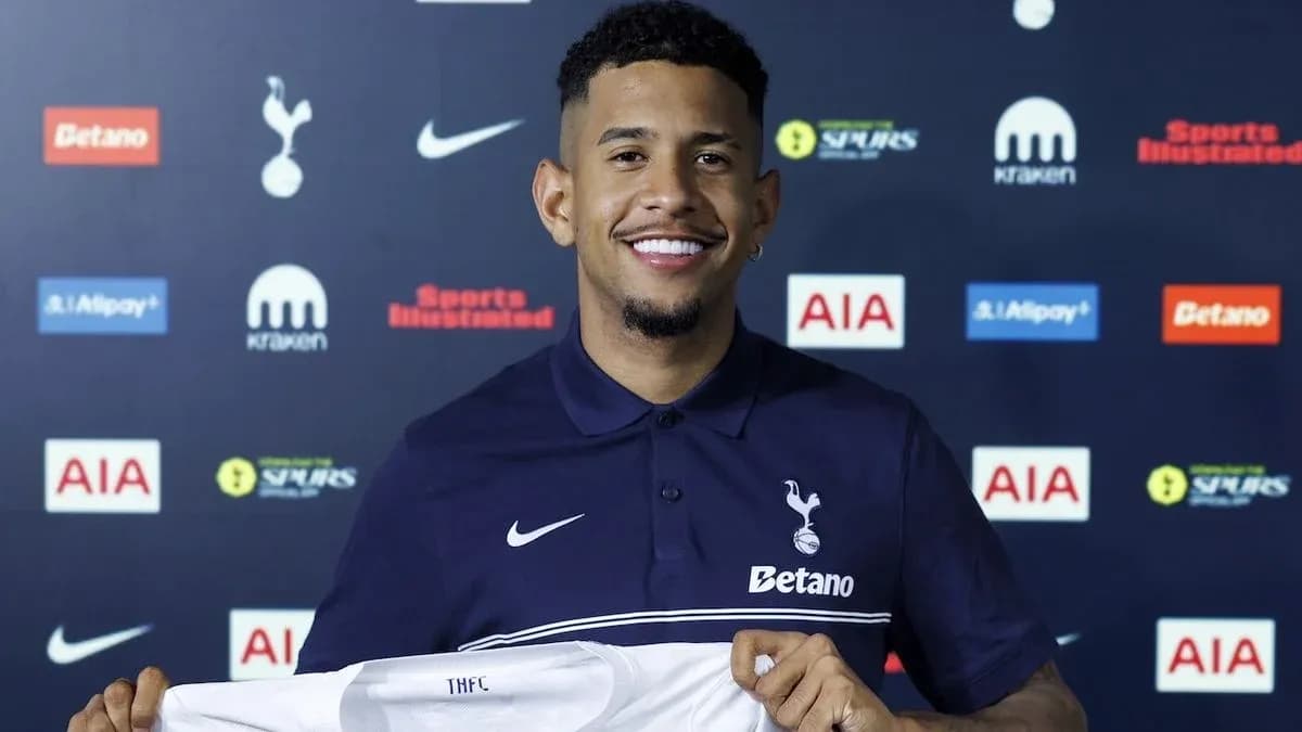Jugador sonriente sosteniendo camiseta de Tottenham