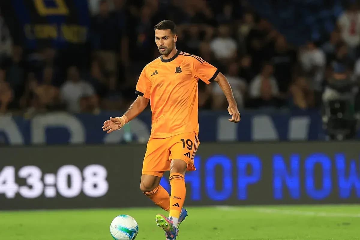 Jugador en uniforme naranja controlando el balón en el campo