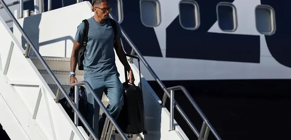 Jugador saliendo del avión con maleta en mano