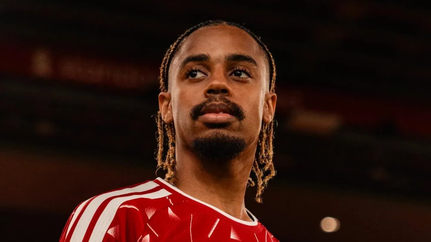 Jugador con camiseta roja posando en el estadio