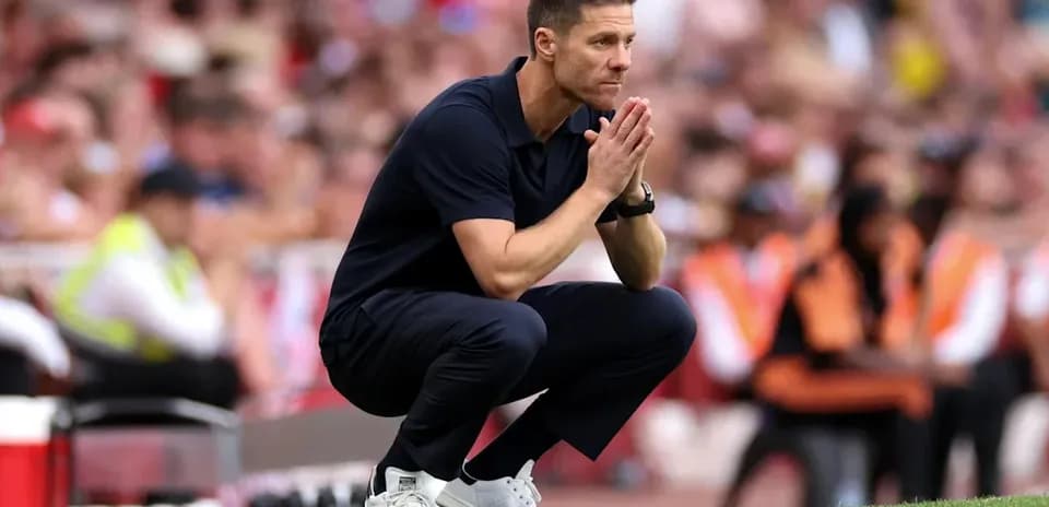 Entrenador en cuclillas durante un partido de fútbol
