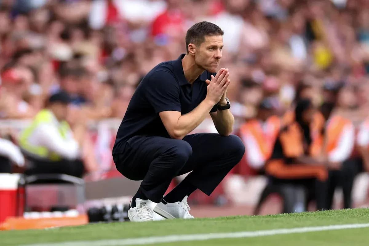 Entrenador en cuclillas durante un partido de fútbol
