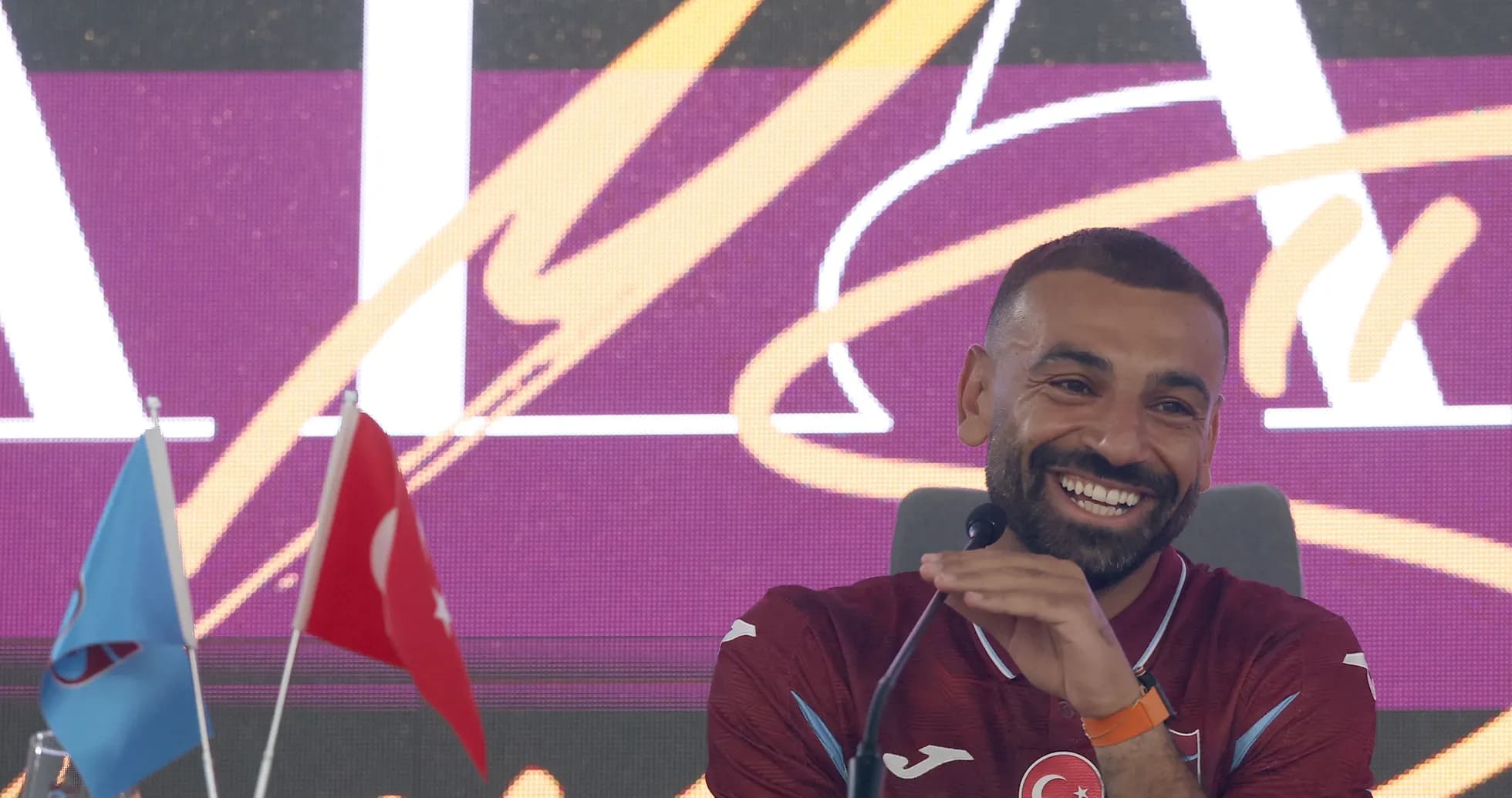 Jugador en conferencia de prensa con banderas detrás