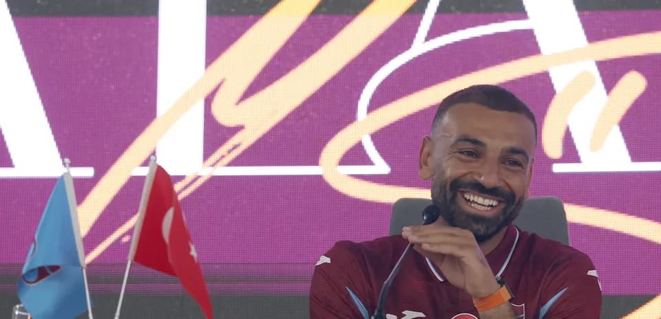 Jugador en conferencia de prensa con banderas detrás