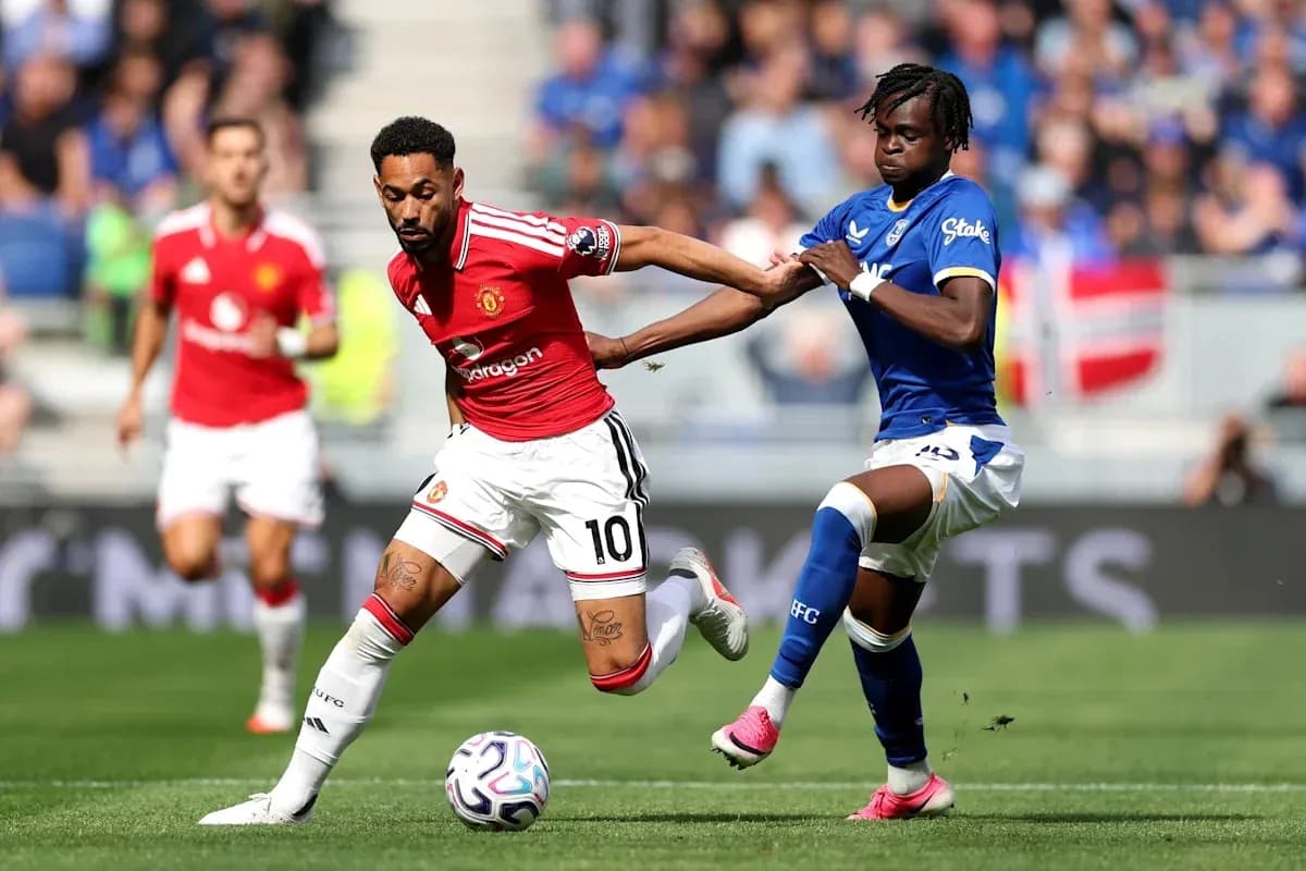 Jugador de Manchester United driblando mientras es marcado