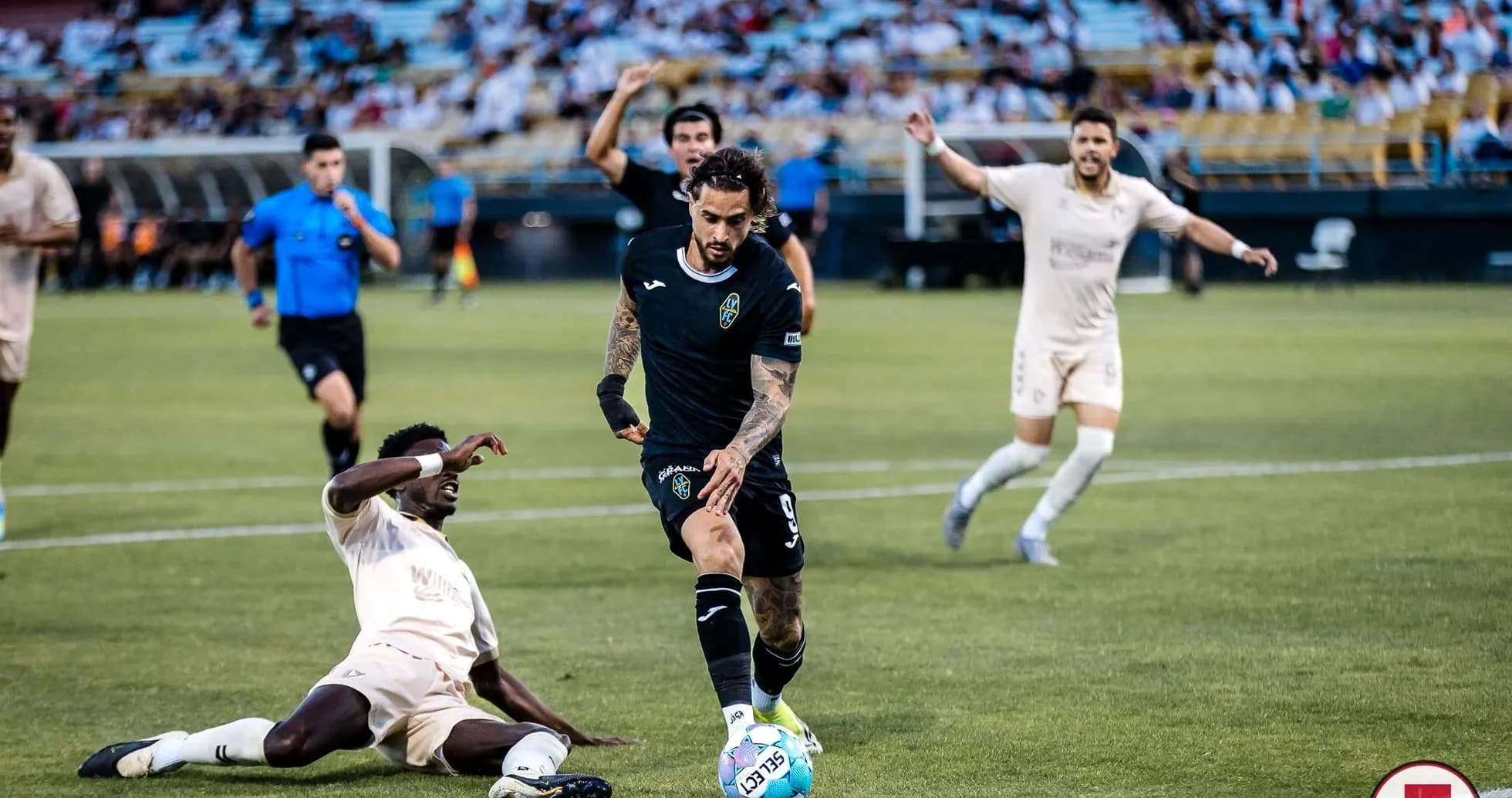Jugador driblando mientras otro cae al suelo