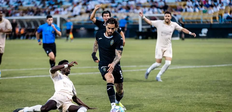 Jugador driblando mientras otro cae al suelo