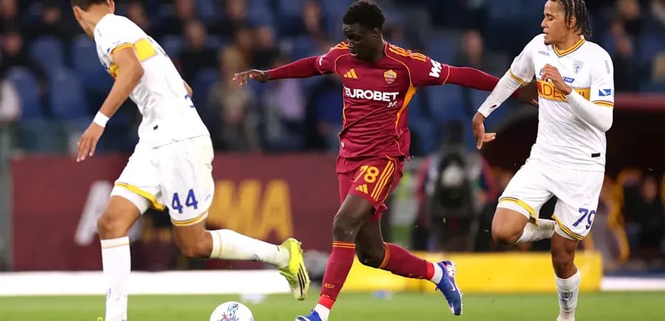 Jugador de la Roma driblando entre dos oponentes