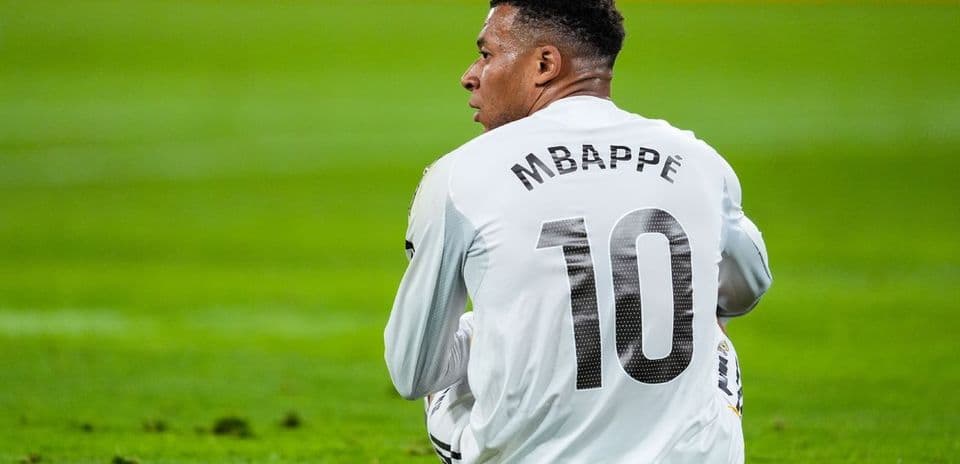 Jugador sentado en el campo con camiseta de Mbappé