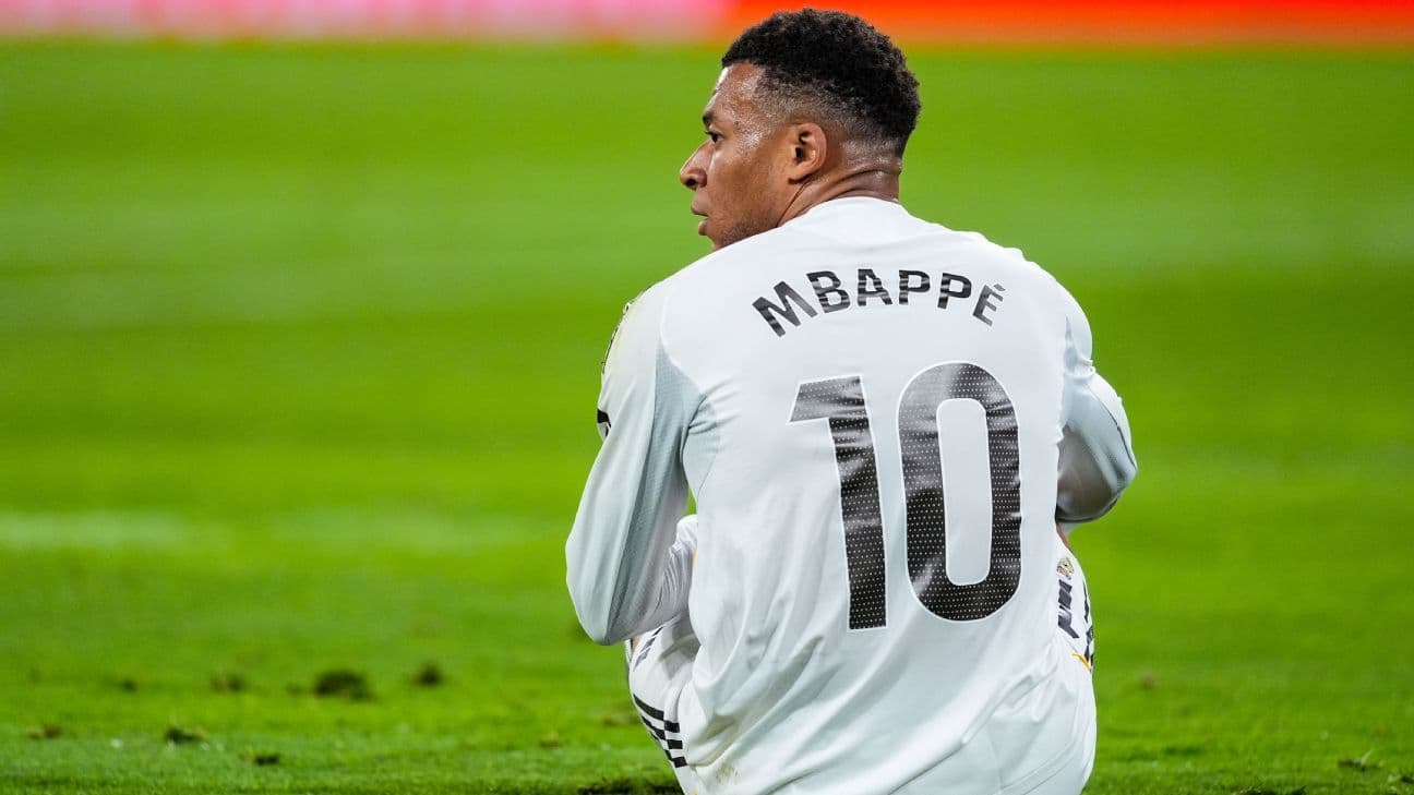 Jugador sentado en el campo con camiseta de Mbappé