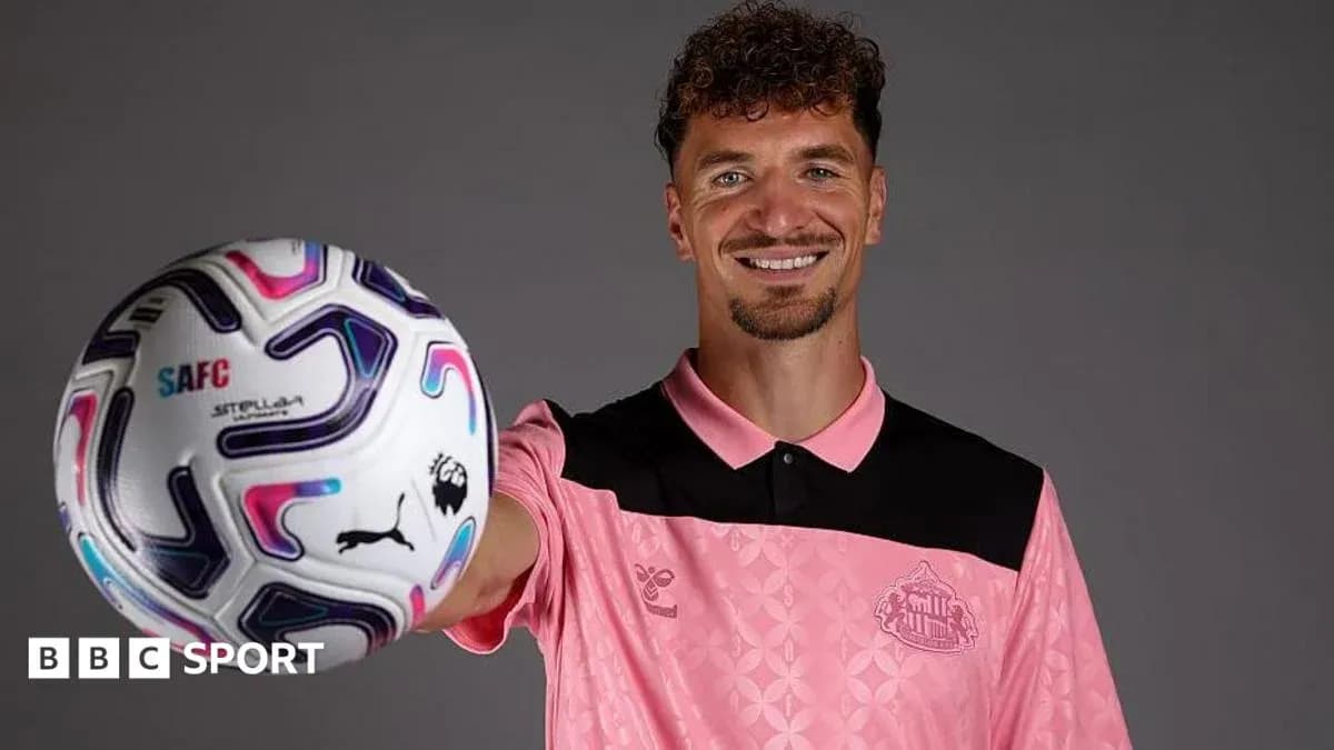 Jugador sosteniendo un balón de fútbol sonriendo