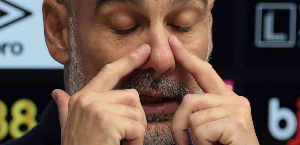 Entrenador tocando su rostro durante conferencia de prensa