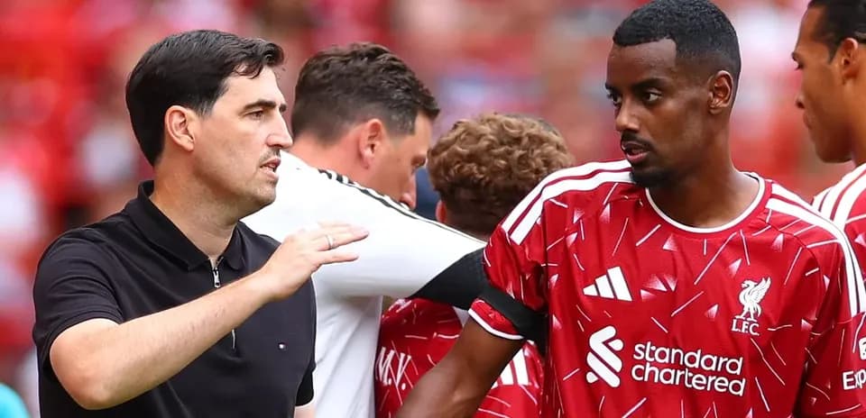 Entrenador hablando con jugador del Liverpool en el banquillo