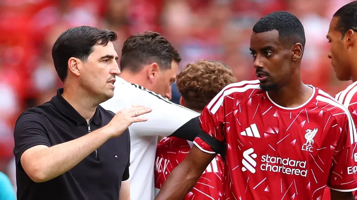 Entrenador hablando con jugador del Liverpool en el banquillo