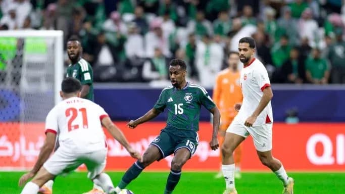 Jugador saudí driblando entre dos oponentes en el campo