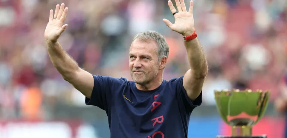 Entrenador saludando junto a trofeo en el estadio
