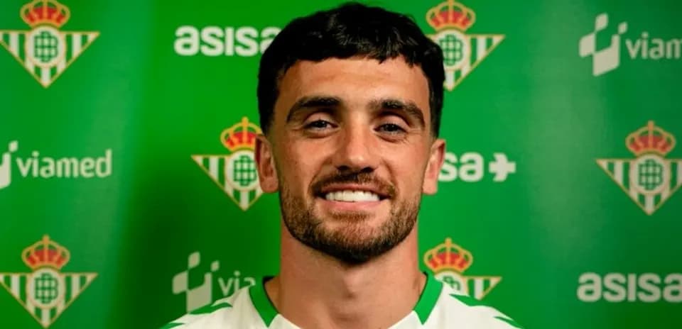 Jugador sonriendo frente a fondo del club Real Betis