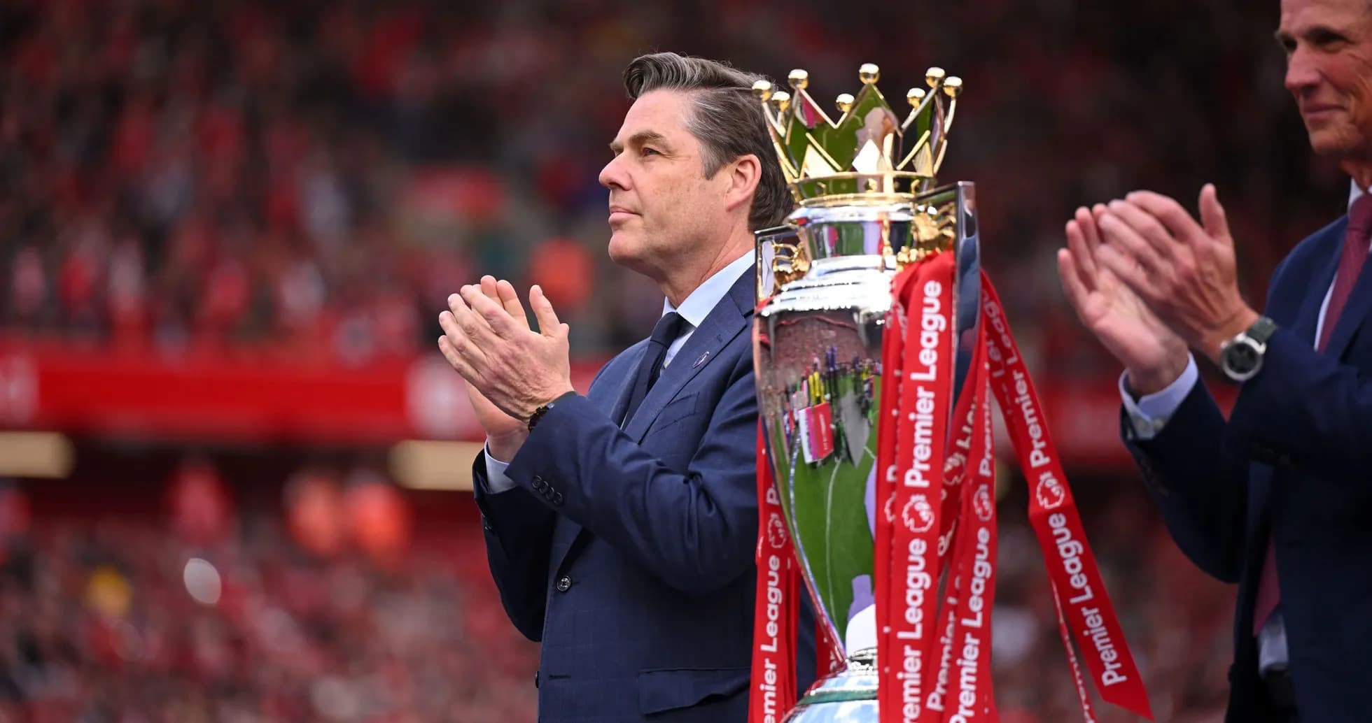 Hombre aplaudiendo junto a trofeo de Premier League