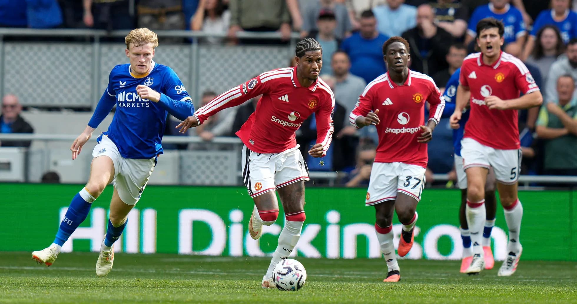 Jugadores de Manchester United corriendo tras balón en partido