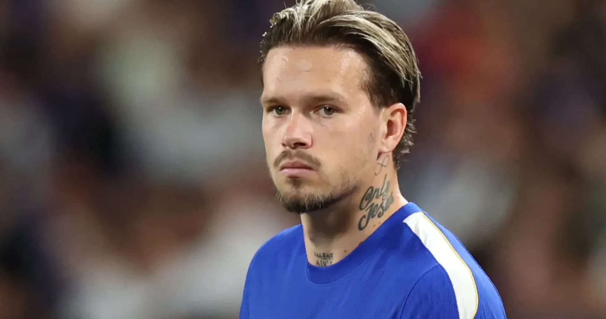 Jugador de fútbol en camiseta azul mirando hacia adelante