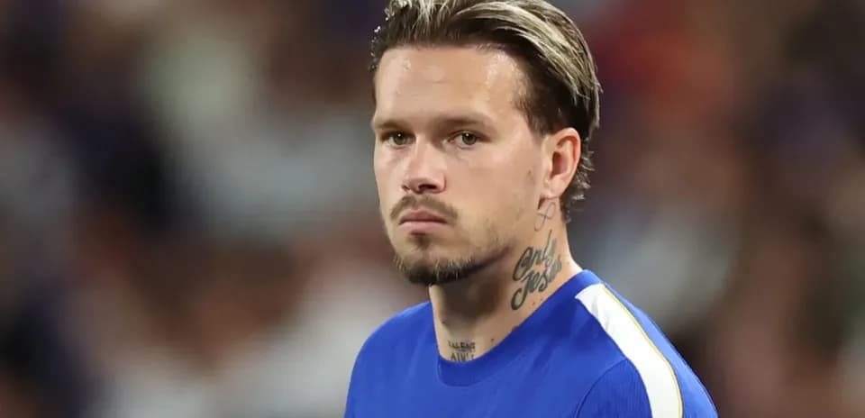 Jugador de fútbol en camiseta azul mirando hacia adelante