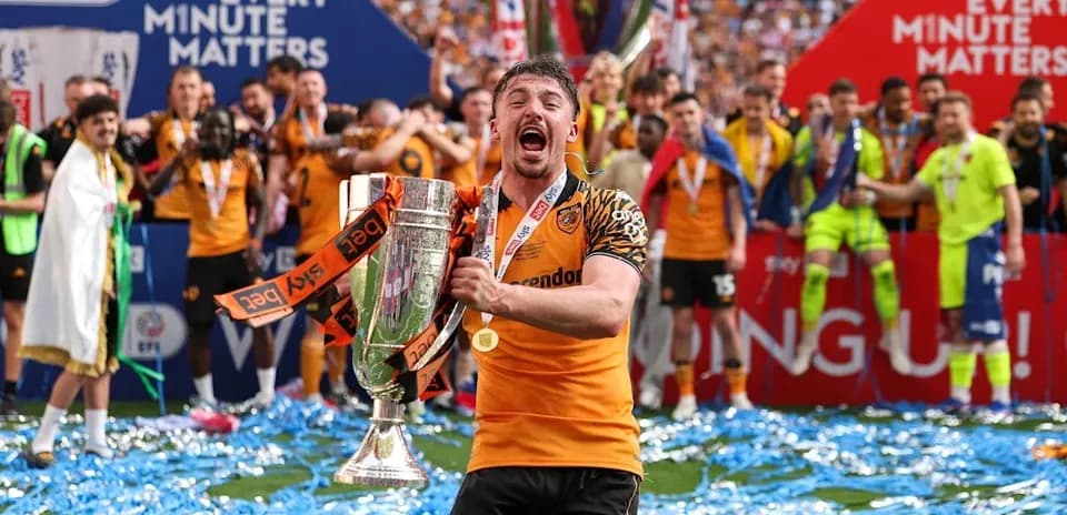 Jugador celebrando con trofeo en campo de fútbol