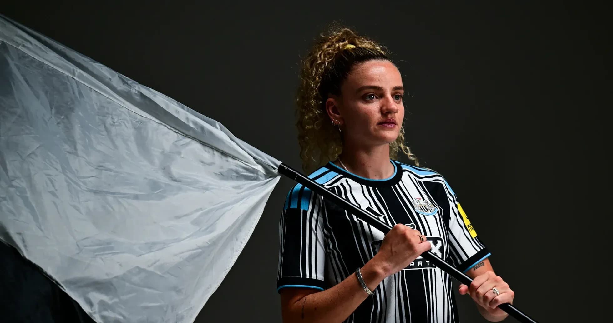 Jugadora con camiseta de Newcastle sosteniendo una bandera